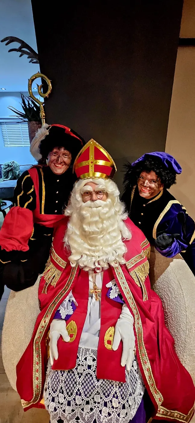 Sinterklaas in een stoel met twee Pieten achter hem